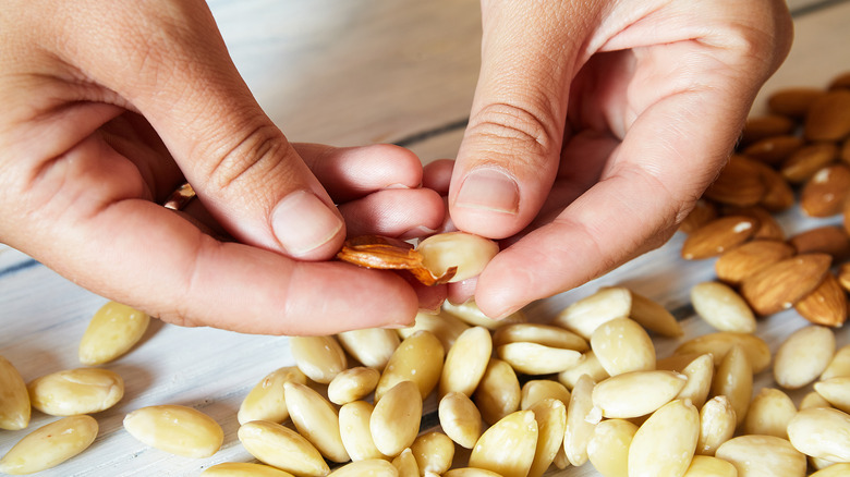 hands removing almond skin