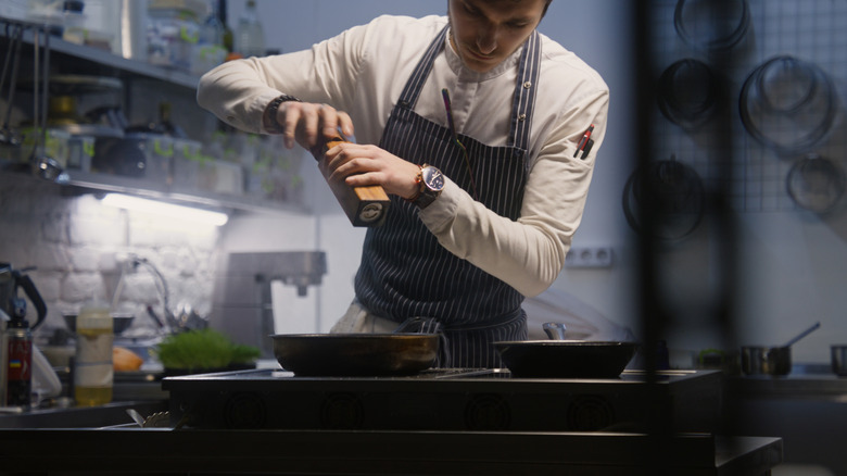 A chef seasoning a dish.