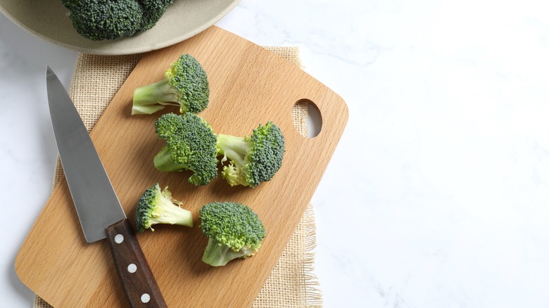 fresh broccoli and knife on cutting board