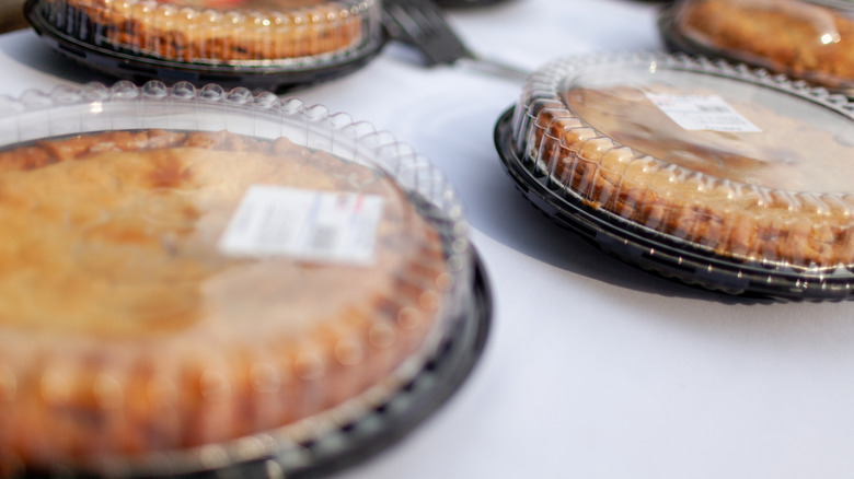 Several store-bought pies with plastic lids on