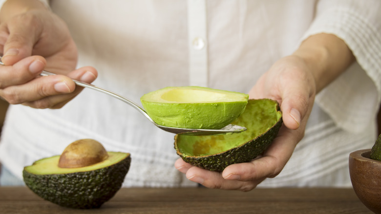 Person scooping avocado meat out of its peel