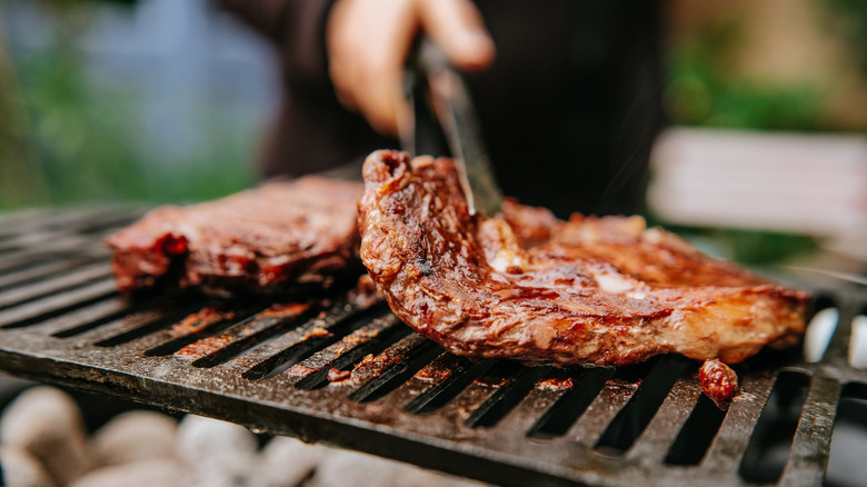 Person flipping bbq meat on grill