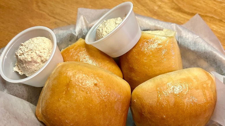 A basket of Texas Roadhouse rolls with a side of butter