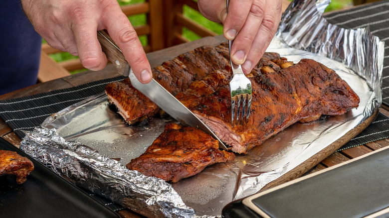 man cutting grilled pork ribs