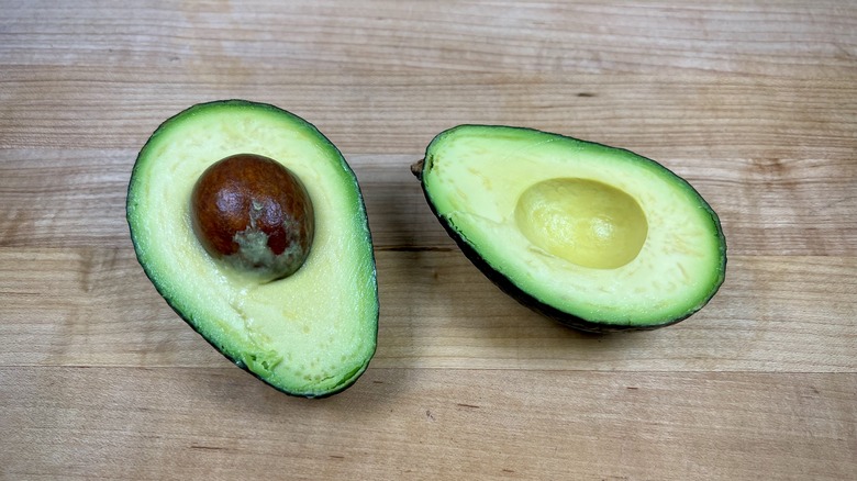 Halved avocado on cutting board