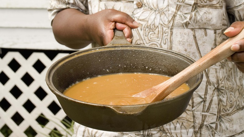 man reheats gravy in pan