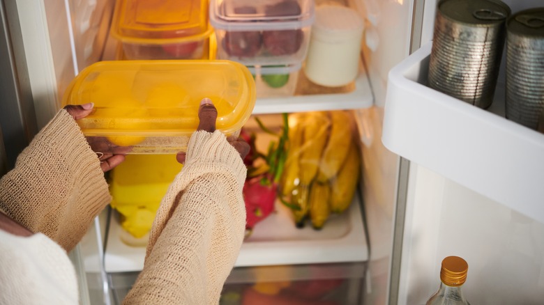 Hands placing container in fridge