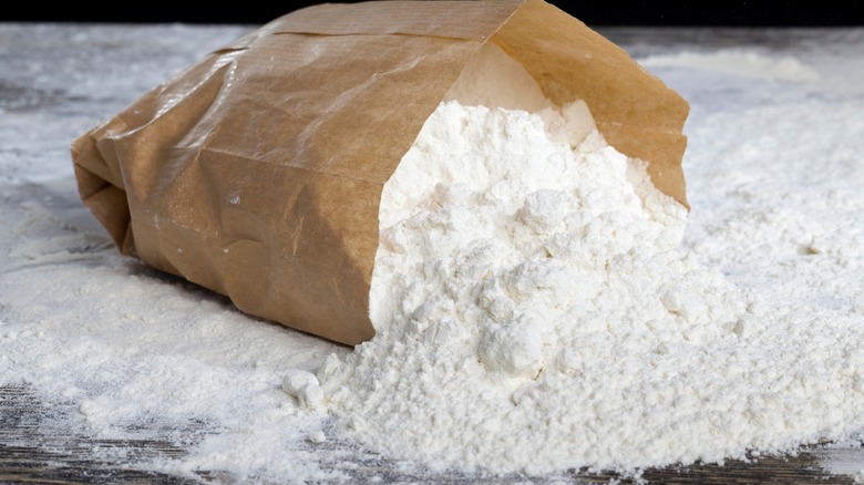 Paper bag with flour spilled on table