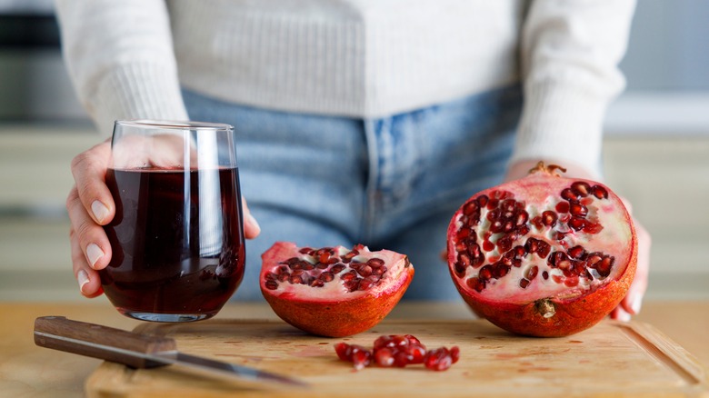 Person displaying sliced pomegranate and cup of juice