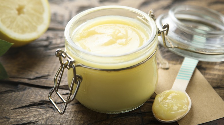 An open glass jar of lemon curd with spoon