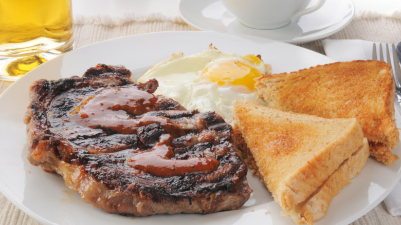 t-bone steak and eggs with toast on white plate