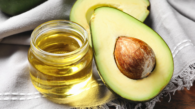 sliced avocado next to jar of olive oil