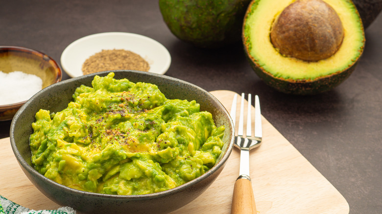 fresh guacamole next to avocados