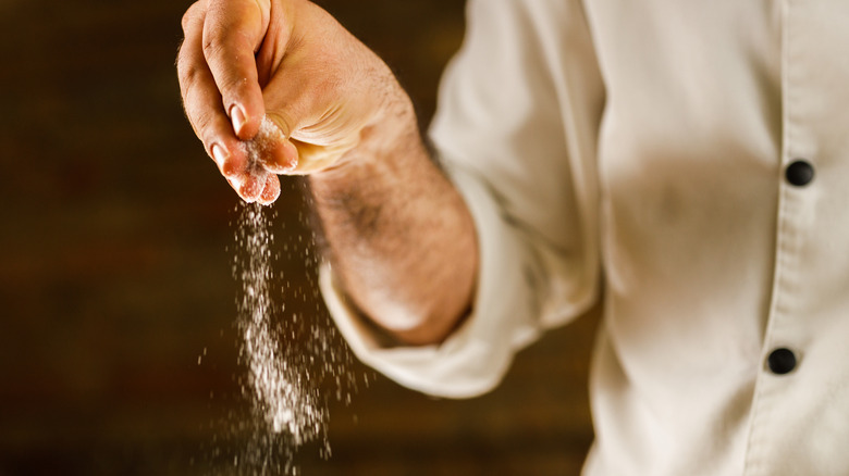 Chef sprinkling salt in kitchen