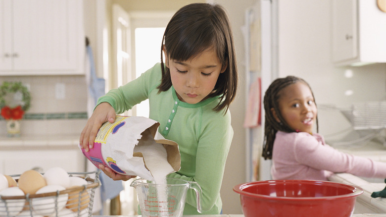 Kids pouring white sugar measurement