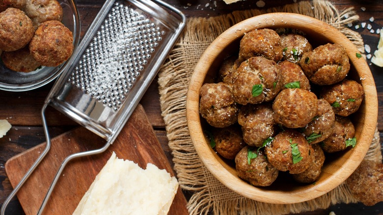 Overview of meatballs in bowls with Parmesan and grater