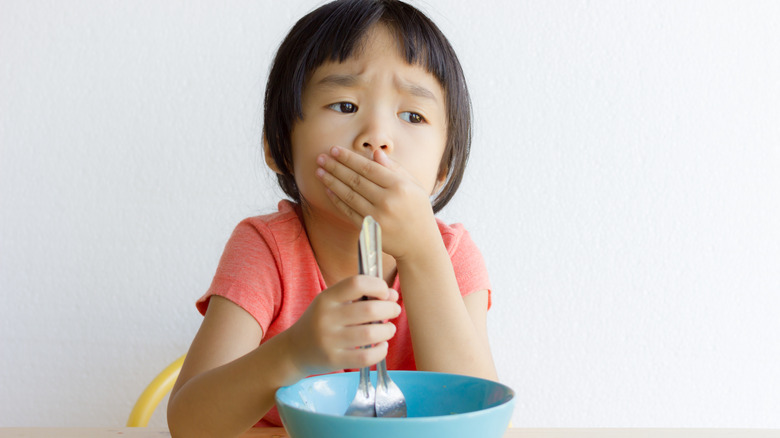 girl gags over cereal bowl