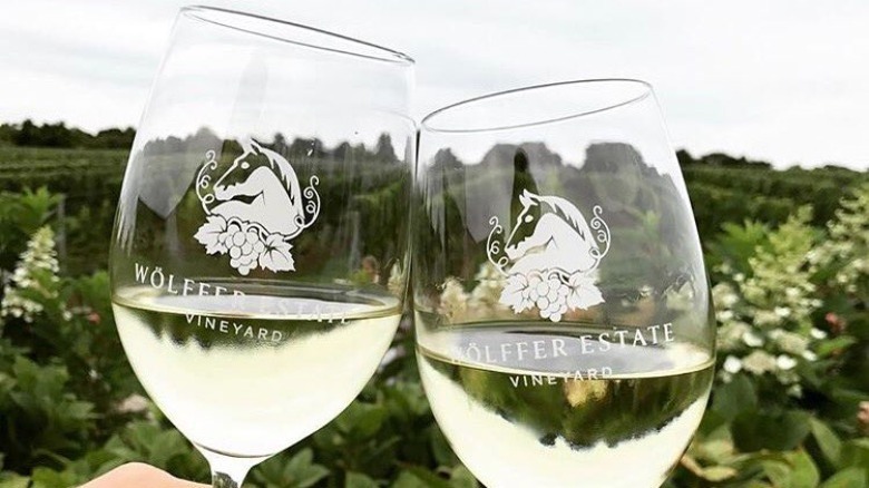 hands holding Wölffer Estate wine glasses