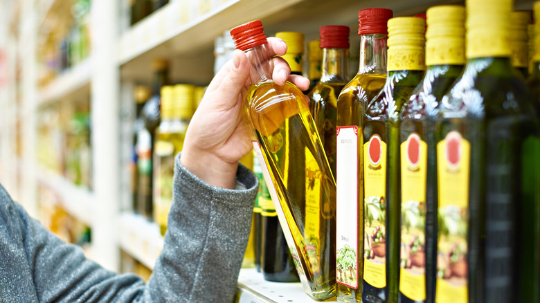 Consumer picking up a bottle of olive oil