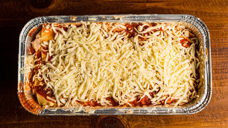 Frozen lasagna in a rectangular aluminum pan on wood surface