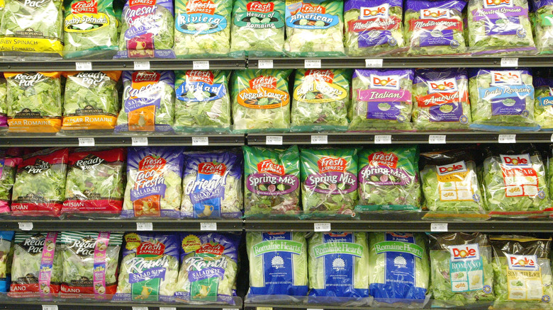 Grocery store shelf filled with bagged salad greens from Dole and Fresh Express