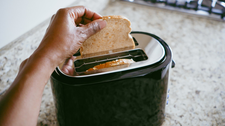 putting a slice of bread into a toaster