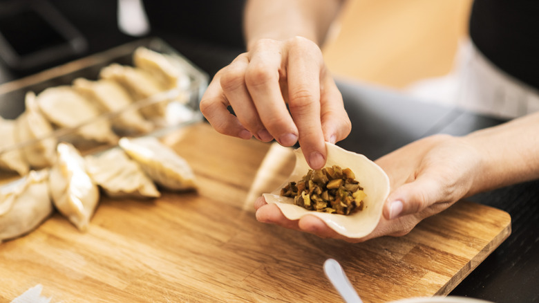 person folds dumplings at home