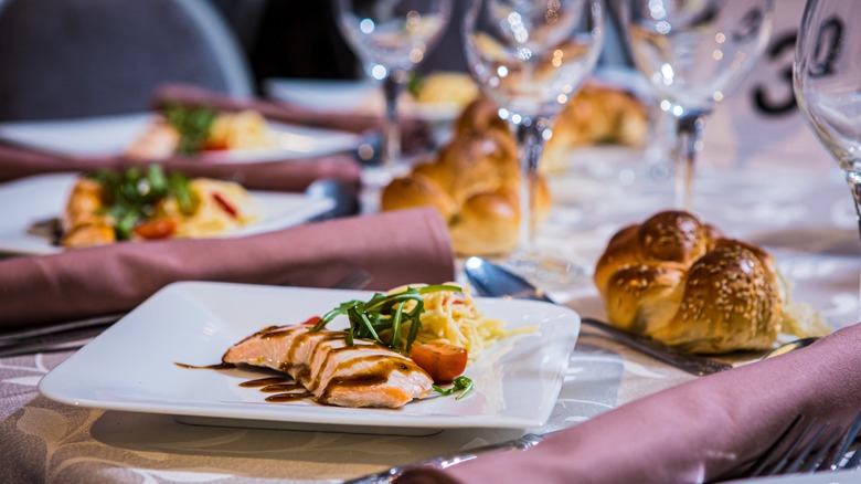 Elegantly plated salmon with challah roll at wedding