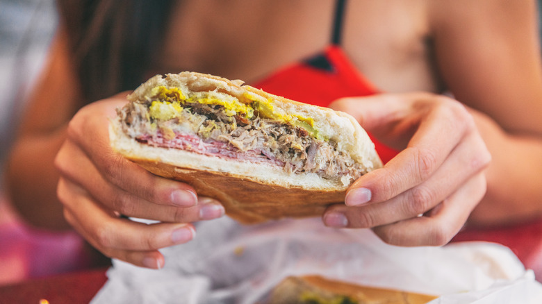 Hands holding half Cuban sandwich