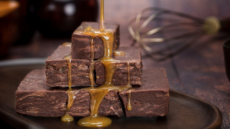 Stacked fudge pieces being drizzled with caramel sauce