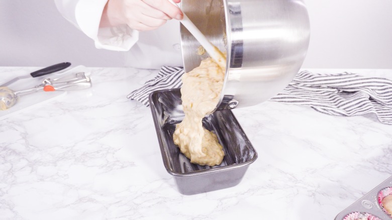 Pouring banana bread batter into a greased pan 