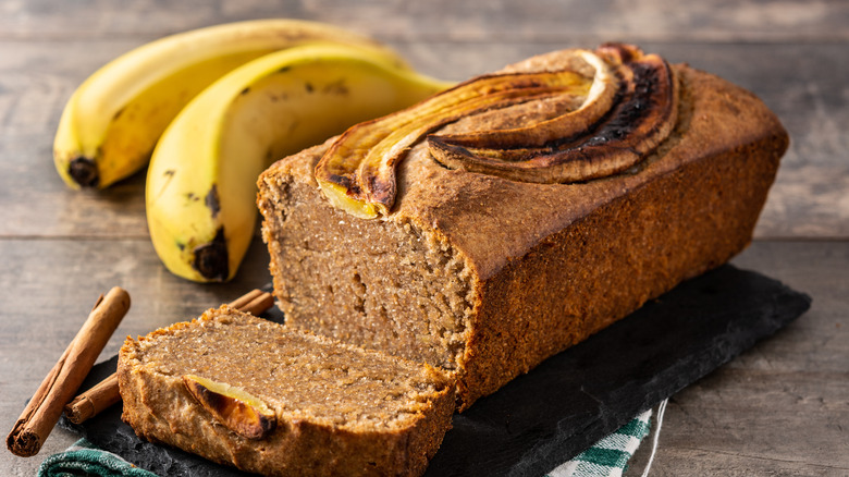 A loaf of banana bread with bananas in the background 