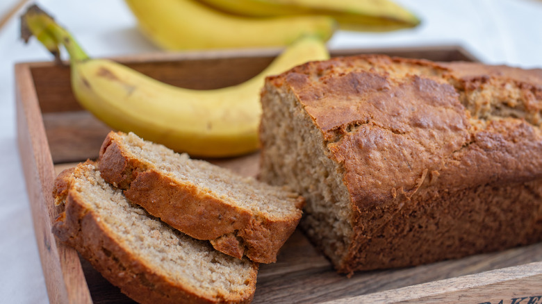 A loaf of banana bread with bananas in the background