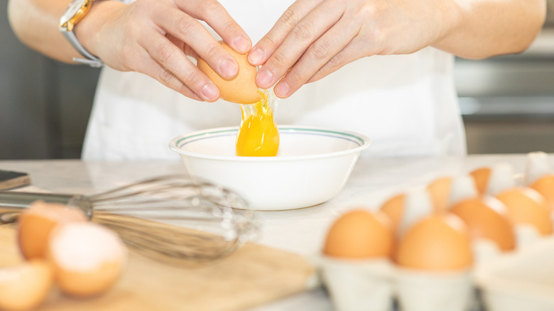 A person cracking an egg into a bowl