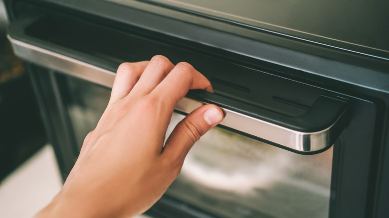 hand opening the oven