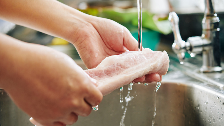 woman washing meat in sink