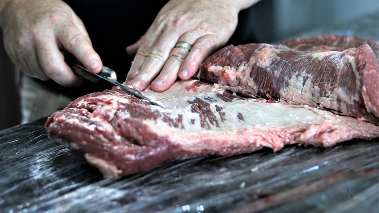 Raw brisket being trimmed