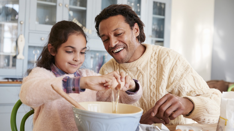 father and daughter cracking an egg