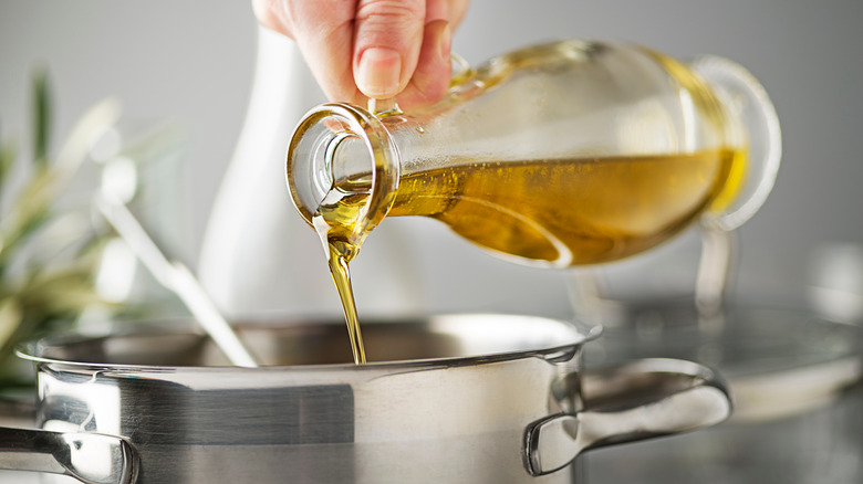 hand pouring olive oil into pot