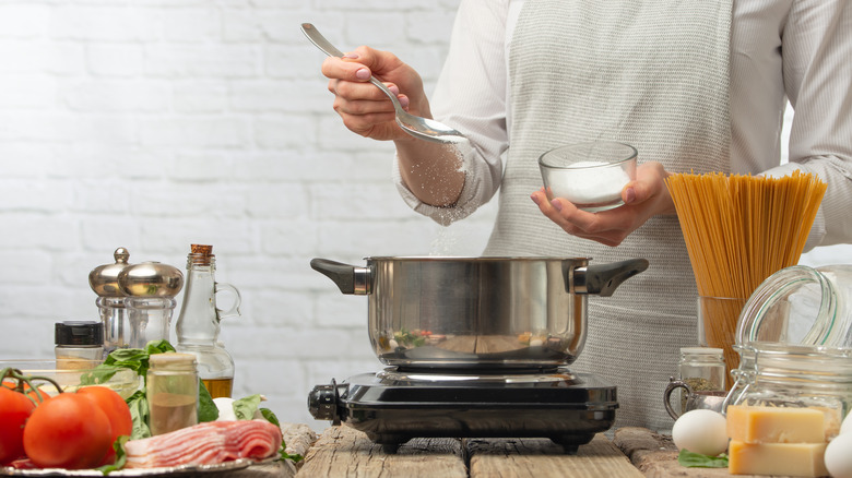 person salting pasta water