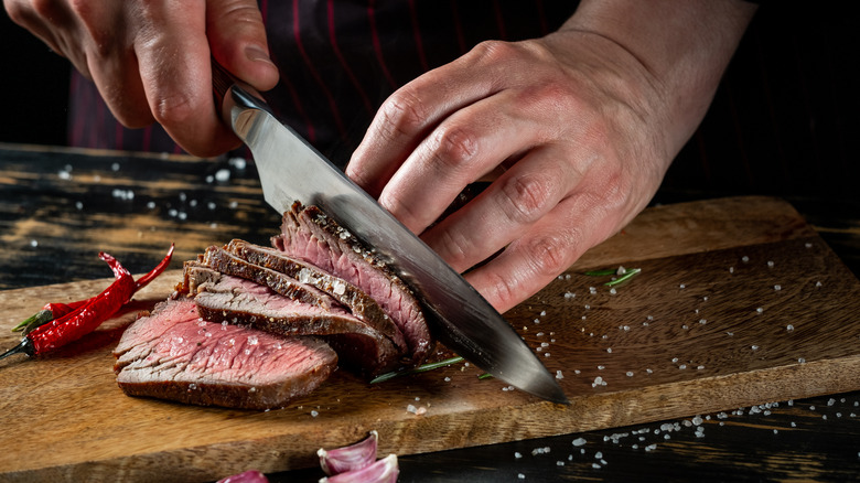 Person cutting meat with knife