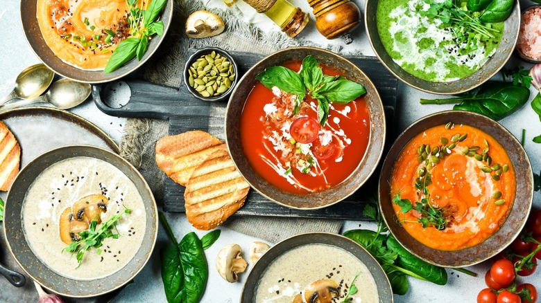 Top-down view of several puréed soups and garnishes on a table