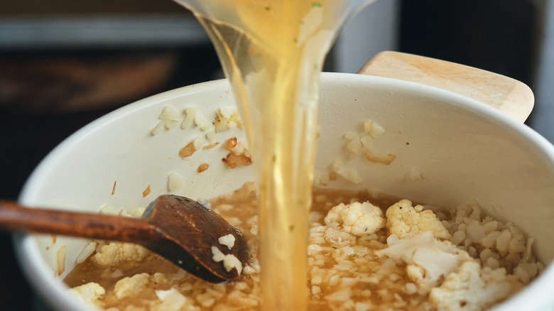 Broth being poured back into a pot of cauliflower cream soup