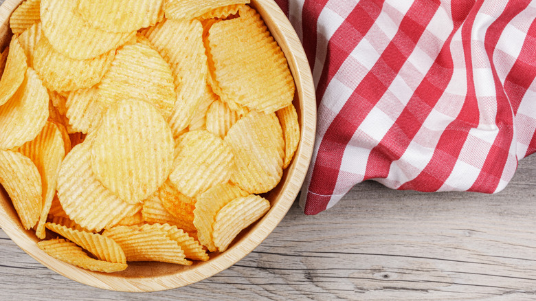A bowl of cheddar and sour cream chips on red and white cloth