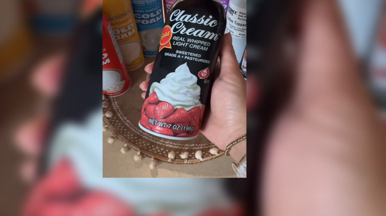 Someone holding a canister of Classic Cream Real Whipped Light Cream