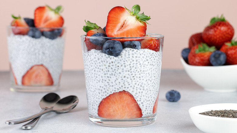 glass cups of chia pudding layered with fresh strawberries and blueberries