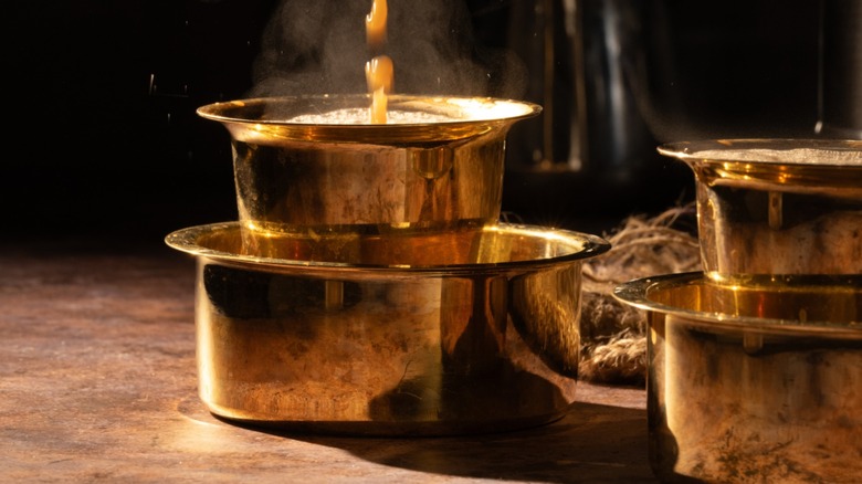 South Indian filter coffee being brewed against a dark background