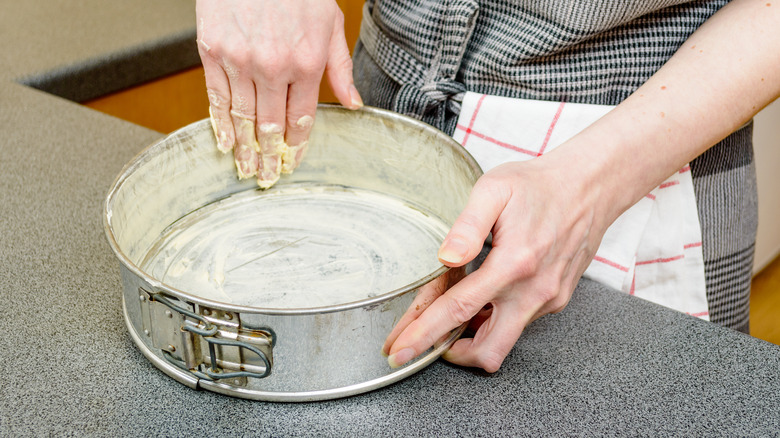 woman buttering cake pan