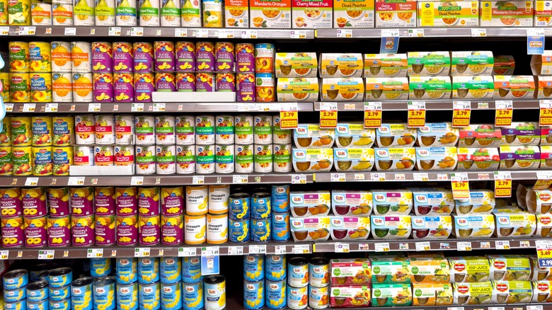 Grocery store shelves of various canned fruits