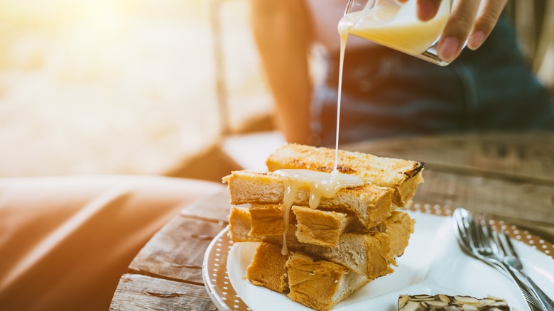 Pouring condensed milk over toast